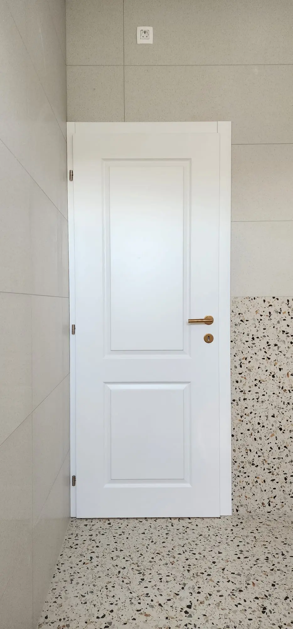 Bijela unutarnja vrata sa zlatnom kvakom i terrazzo podom u modernom interijeru Archicon Split.
