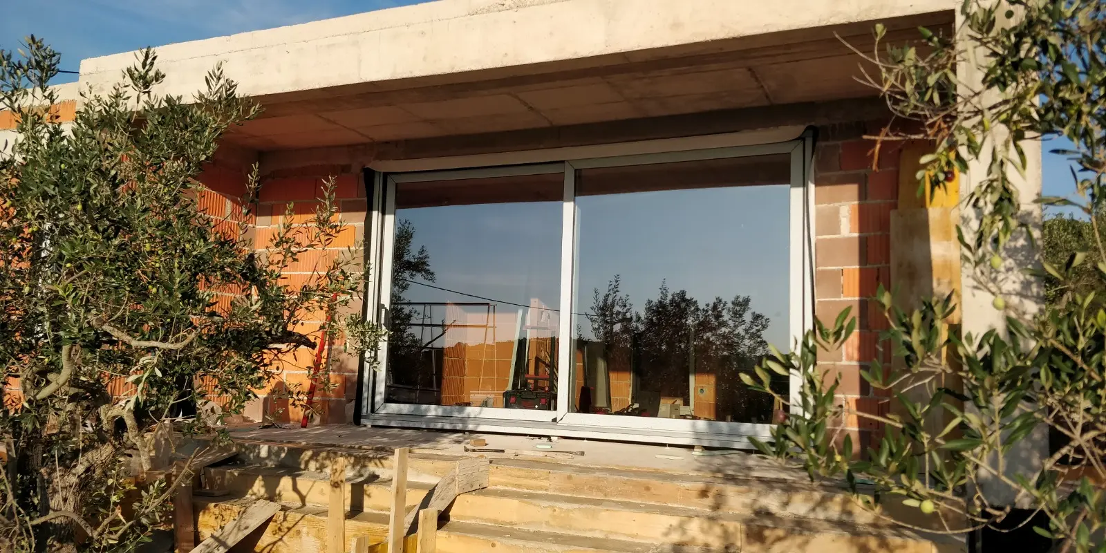 Archicon Split zgrada u izgradnji s ugrađenim bijelim kliznim vratima i maslinama.