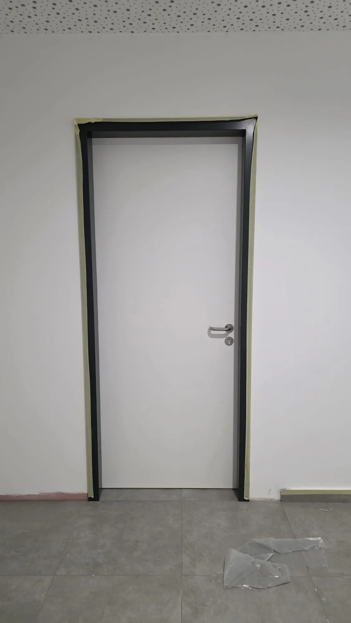 Bijela vrata s crnim okvirom i maskirnom trakom tijekom završnih radova, Archicon Split.