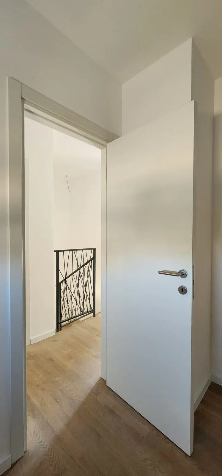 Moderna bijela vrata s drvenim podom i crnom metalnom ogradom, projekt Archicon Split.