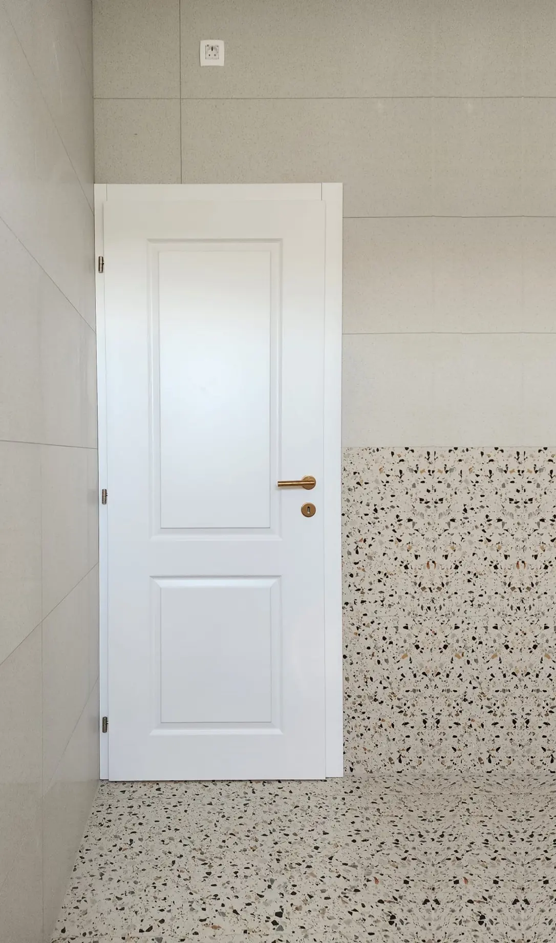 Bijela unutarnja vrata sa zlatnom kvakom, terrazzo pod i zidovi, moderni interijer Archicon Split.