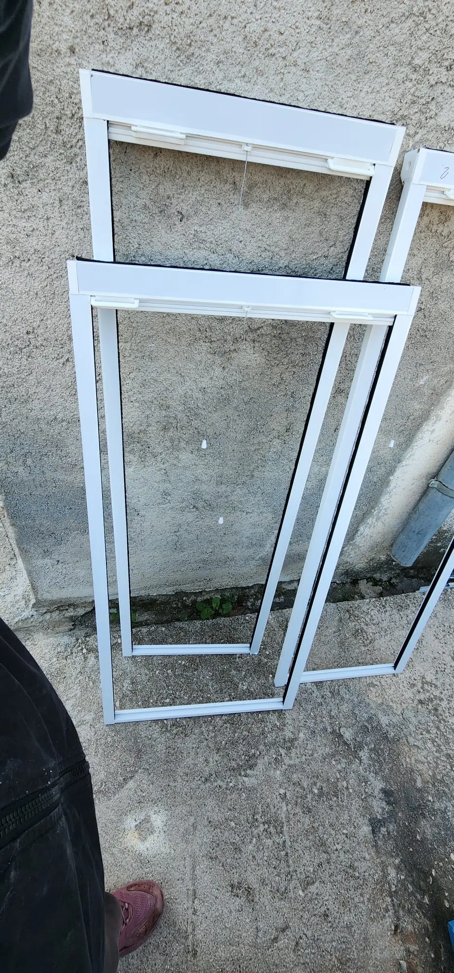 Bijeli aluminijski okviri za komarnike ili rolete Archicon Split naslonjeni na zid