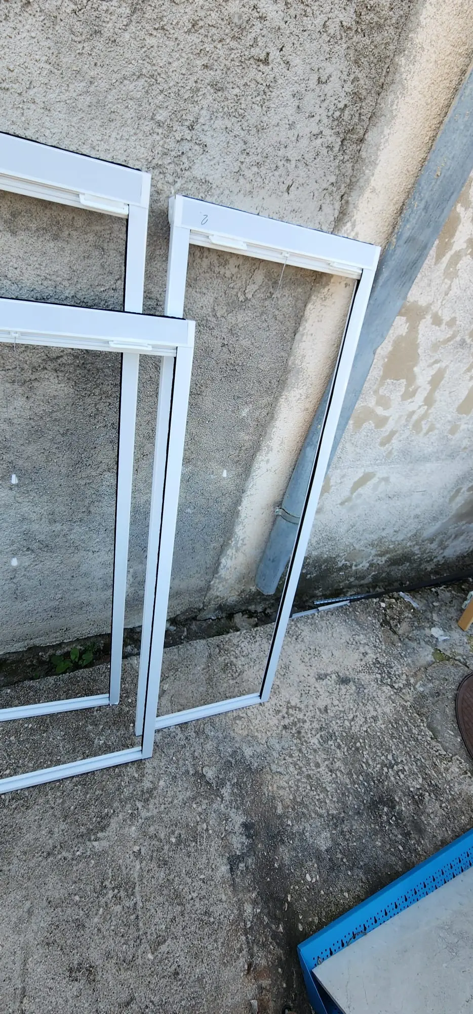 Dva bijela prozorska okvira za komarnike naslonjena na zid, Archicon Split.
