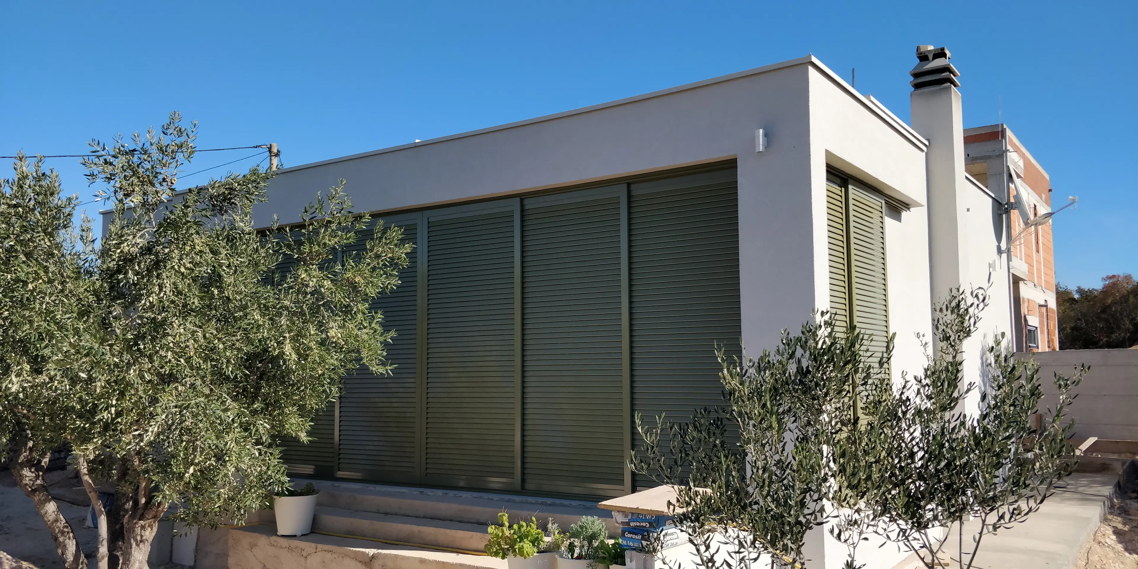 Moderna kuća Archicona sa tamnozelenim griljama i maslinama pod vedrim nebom, Split.