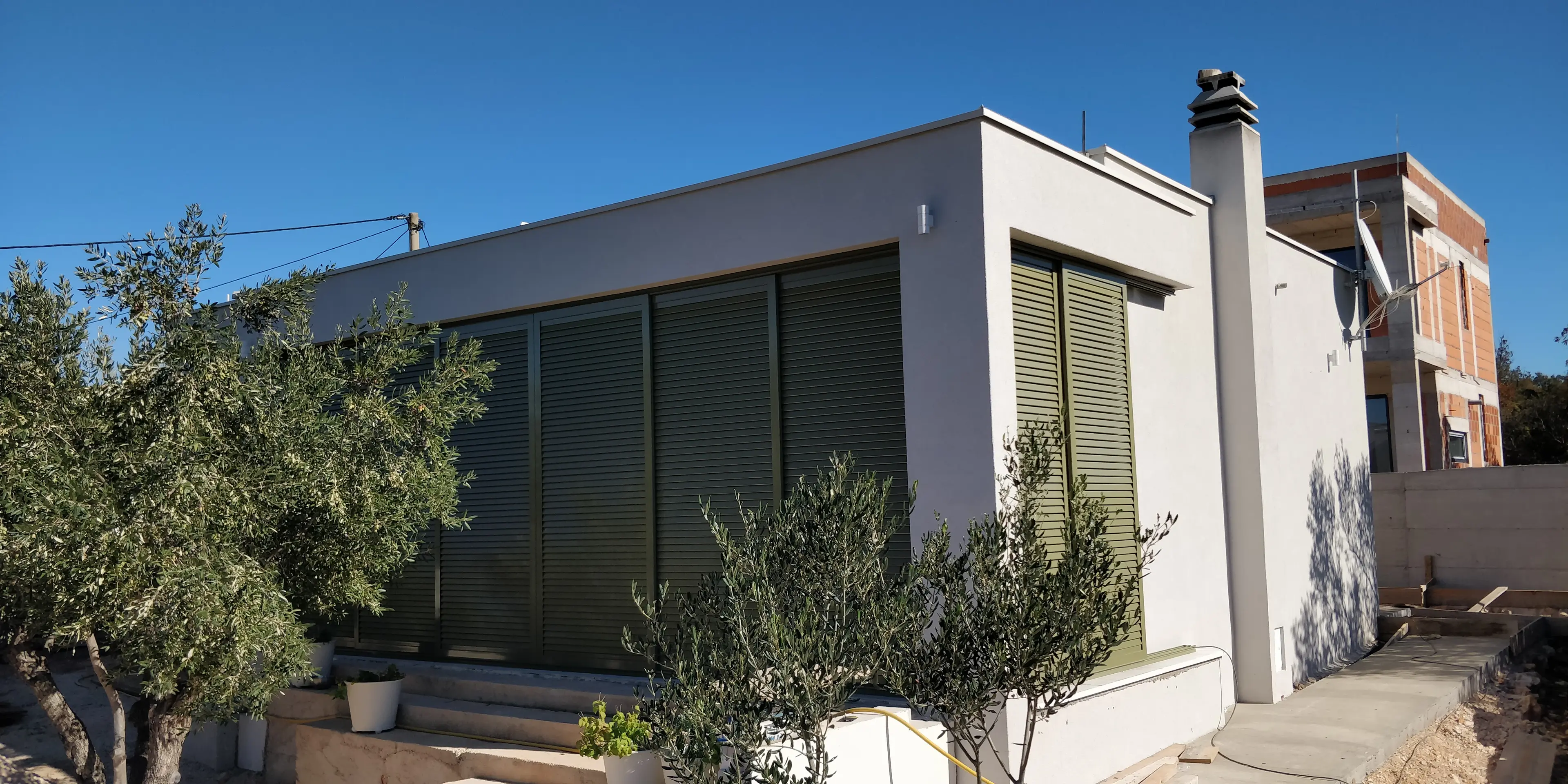 Moderna kuća svijetle fasade s tamnozelenim griljama i maslinama, projekt Archicon Split