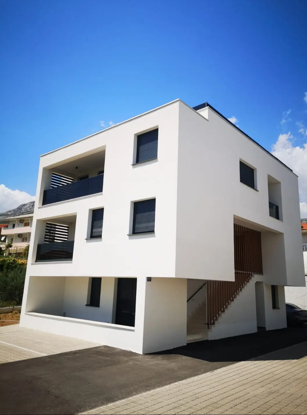 Moderna bijela stambena zgrada Archicon Split s balkonima i vanjskim stubištem pod plavim nebom.