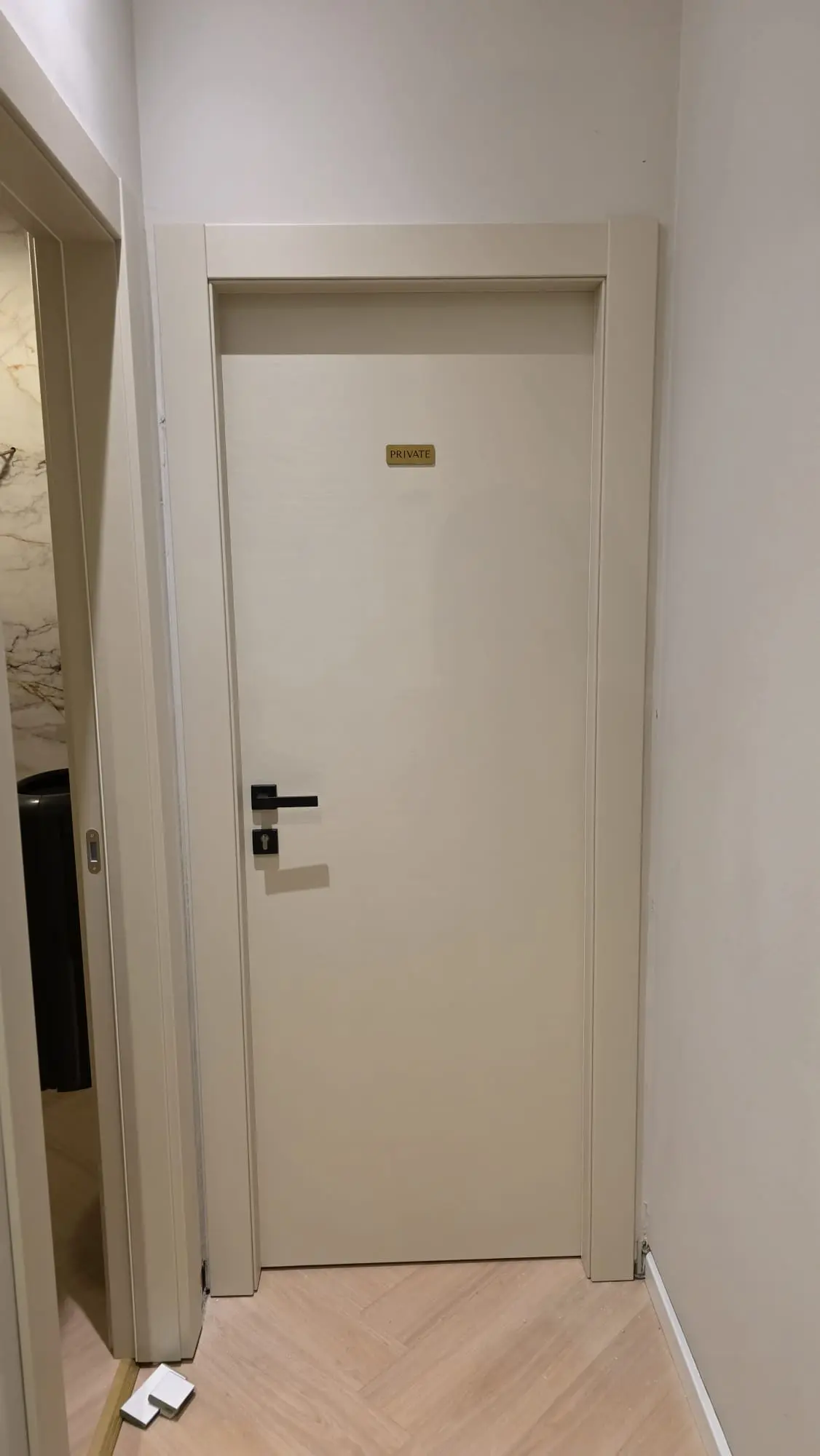 Moderna svijetla vrata Archicon s natpisom 'PRIVATE', crnom kvakom i parketom riblja kost