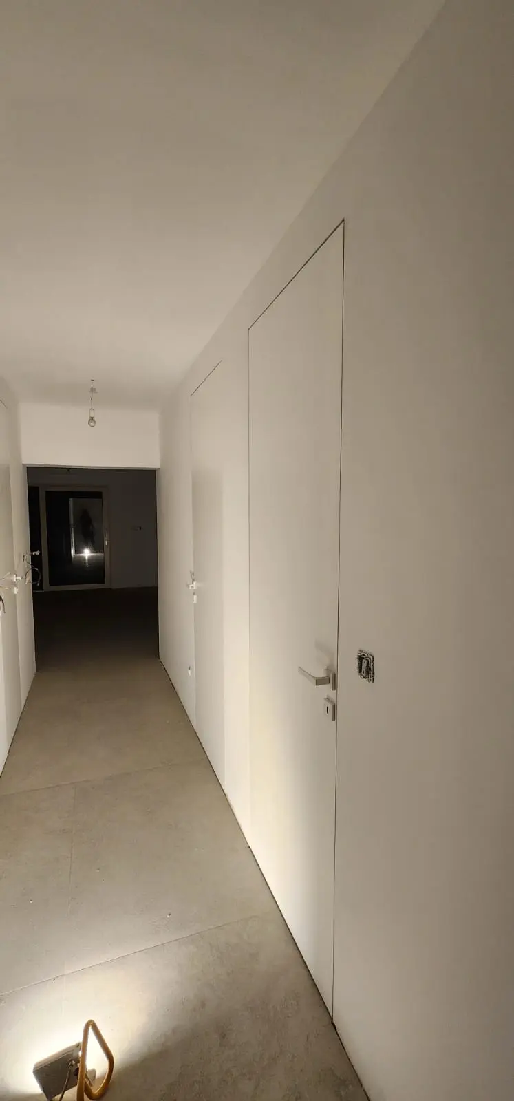 Moderni hodnik s bijelim vratima u ravnini zida i sivim pločicama, projekt Archicon Split