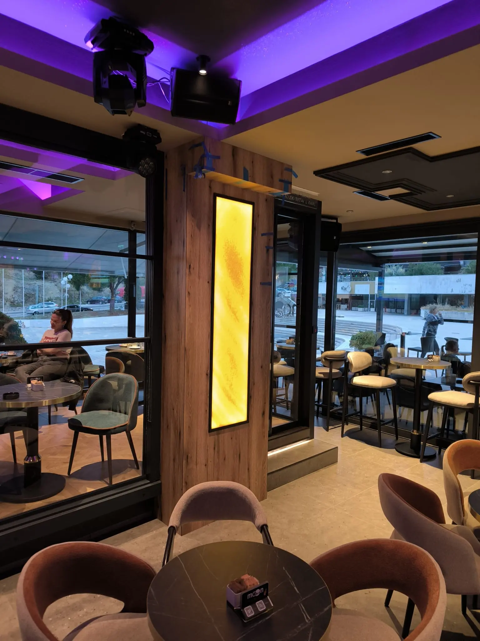 Moderni interijer bara Archicon Split s elegantnim namještajem, drvenim oblogama i ljubičastom rasvjetom.