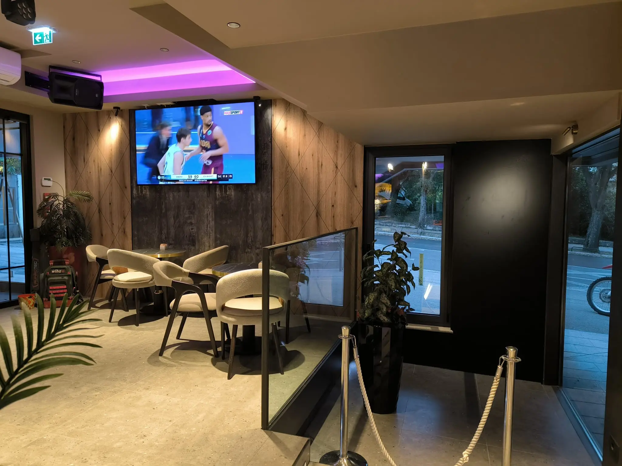 Moderni interijer kafića s TV-om, drvenim zidom i udobnim sjedalima, projekt Archicon Split.