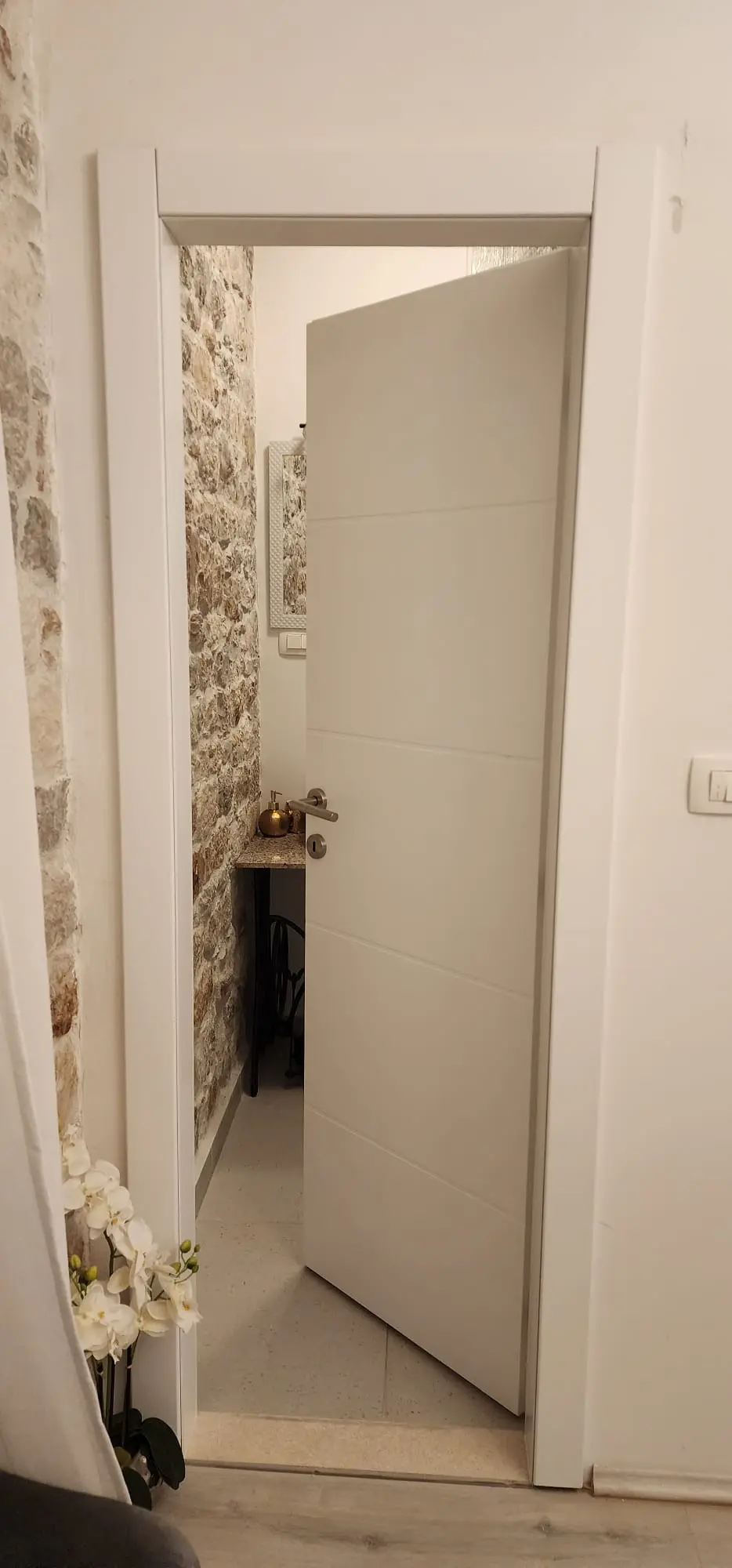 Otvorena bijela vrata s modernom kvakom, kameni zidovi i ogledalo u pozadini, Archicon Split.