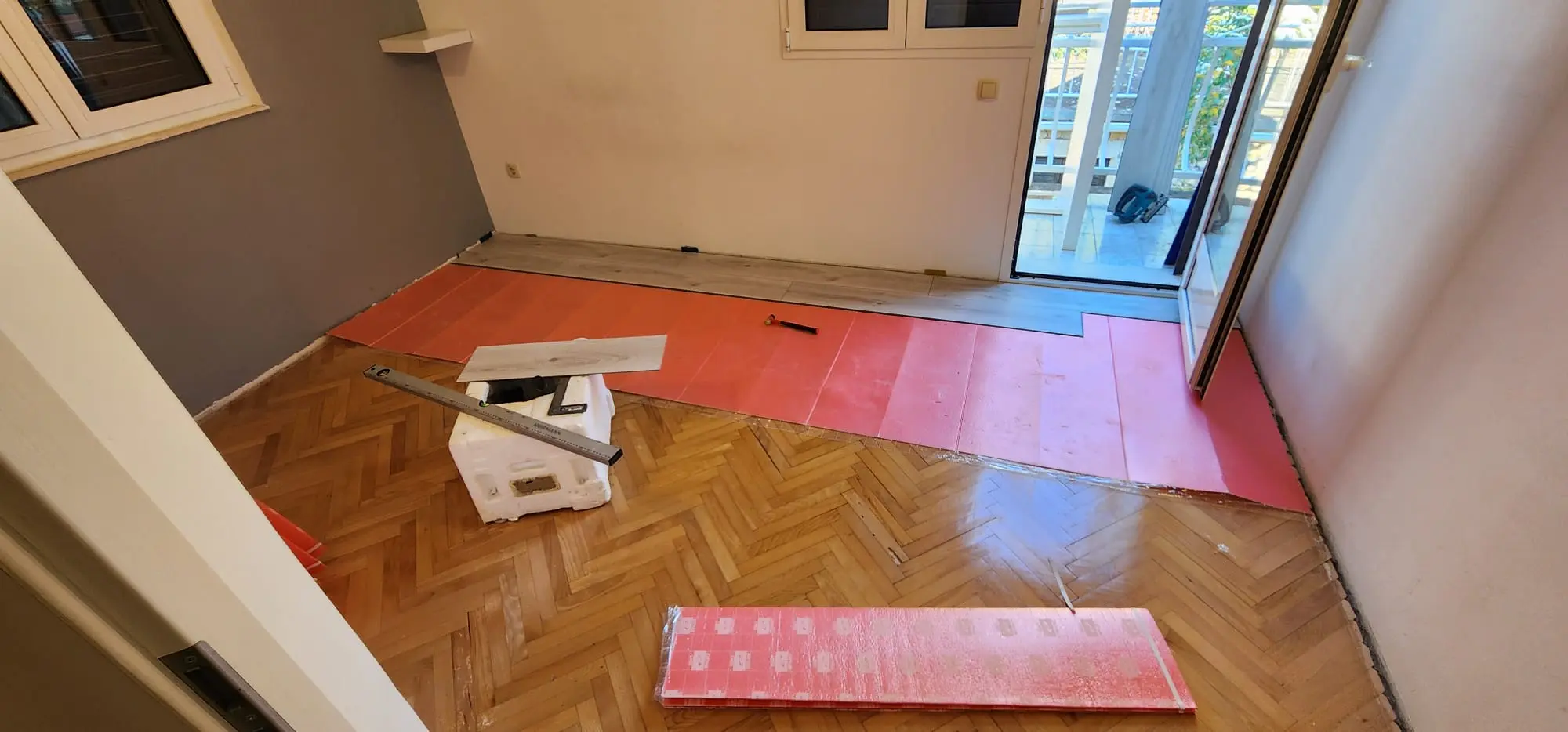 Postavljanje laminata preko starog parketa u sobi, s crvenom podlogom i alatima, Archicon Split