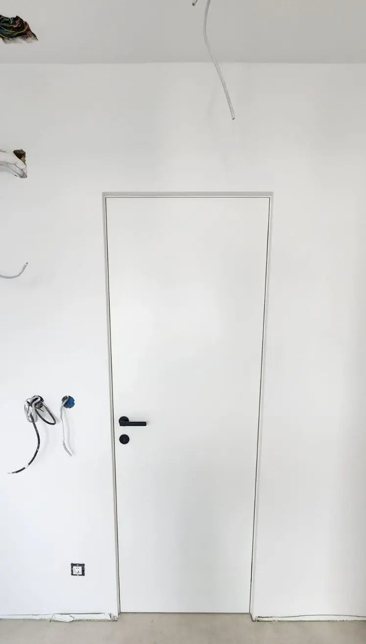 Montaža bijelih unutarnjih vrata s crnom kvakom u prostoru pod radovima Archicon