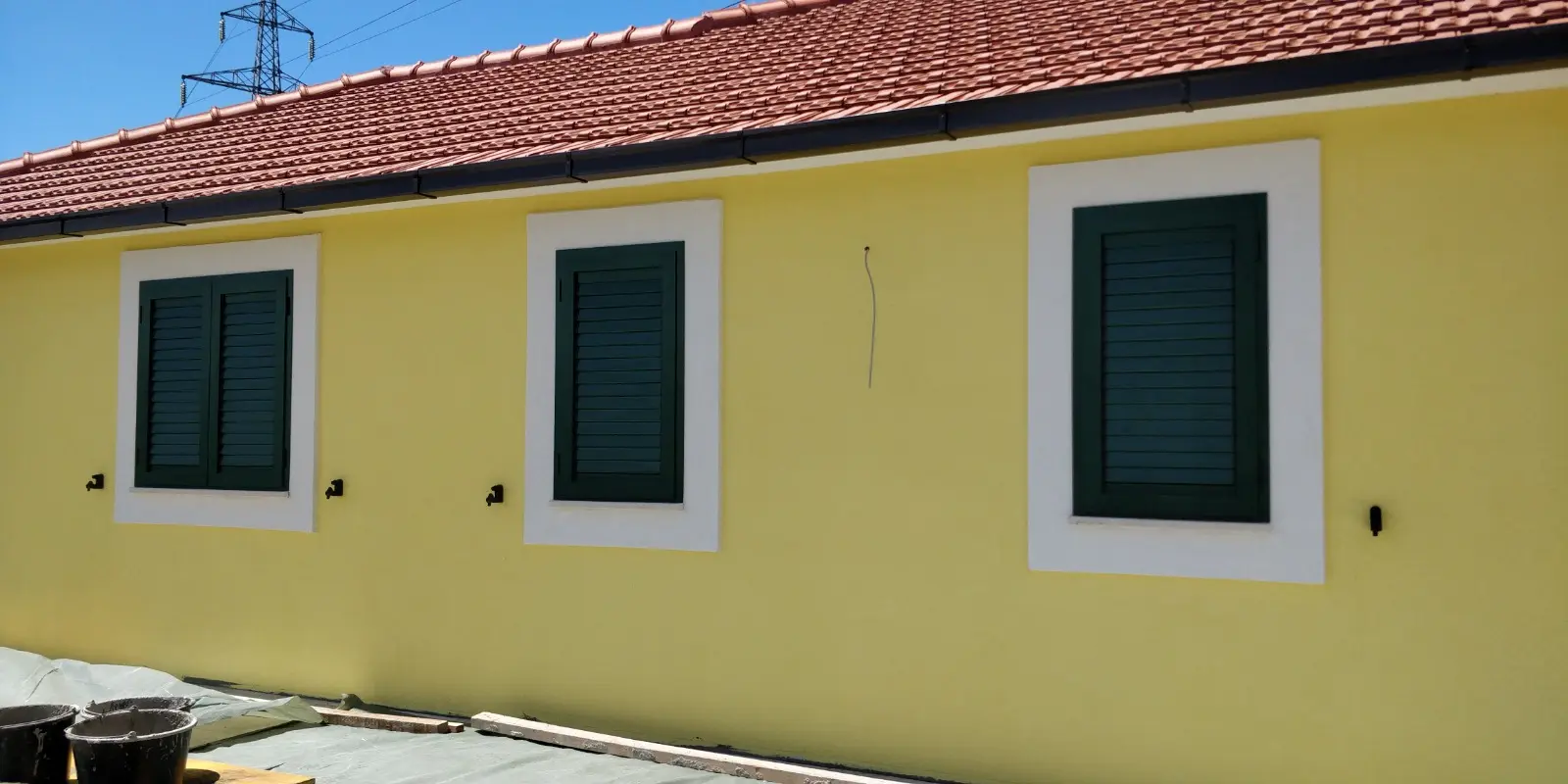 Žuta fasada kuće s tri prozora, tamnozelenim griljama i crvenim krovom, Archicon Split